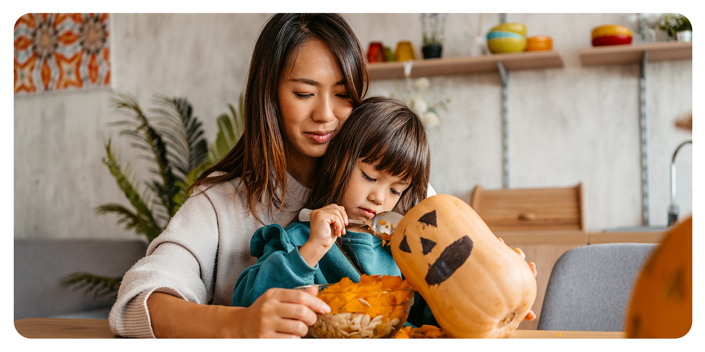 Mother and young daughter decorating a pumpkin at the kitchen table